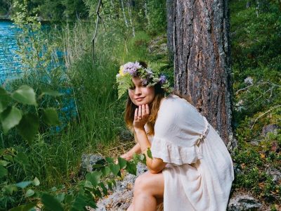 A woman in a white dress sitting next to a tree